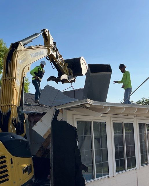 Excavator with grapple demolishing a house roof in the Phoenix area
