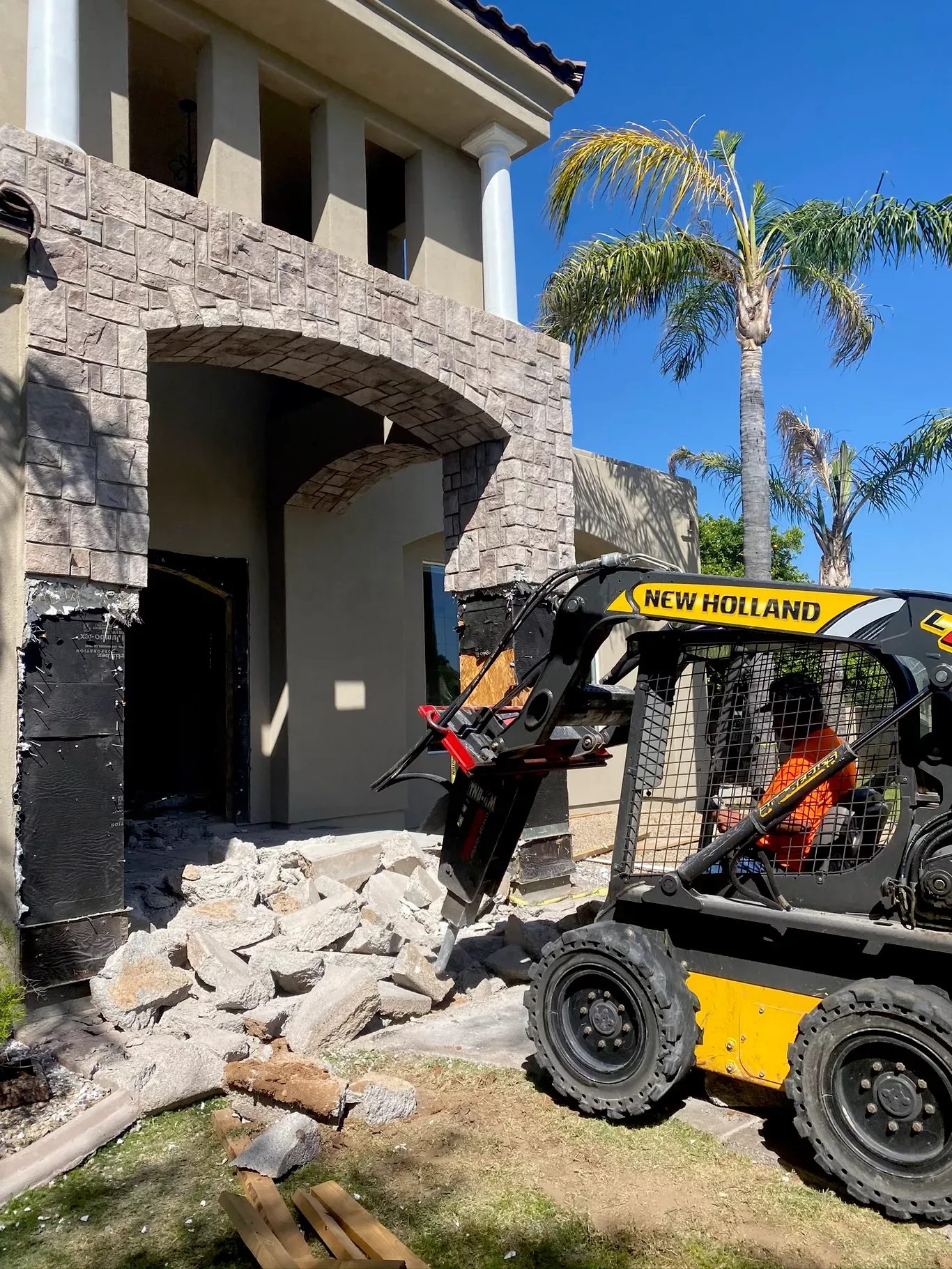 Molina Demolition skid steer breaking a stone entryway during a demolition project in Phoenix, AZ