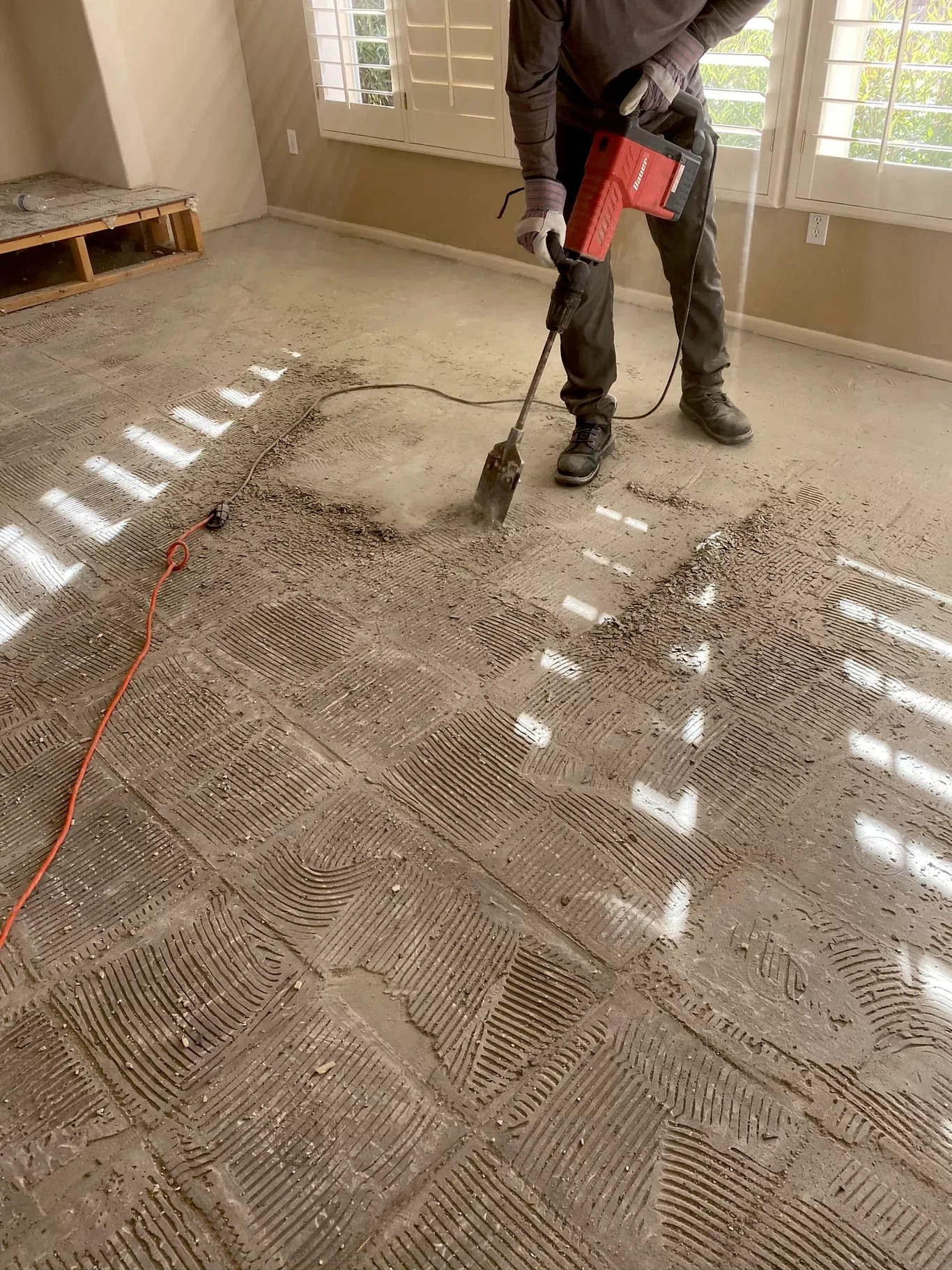 Worker grinding tile thinset off a concrete slab